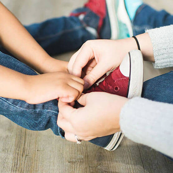 A child learning to tie a shoe