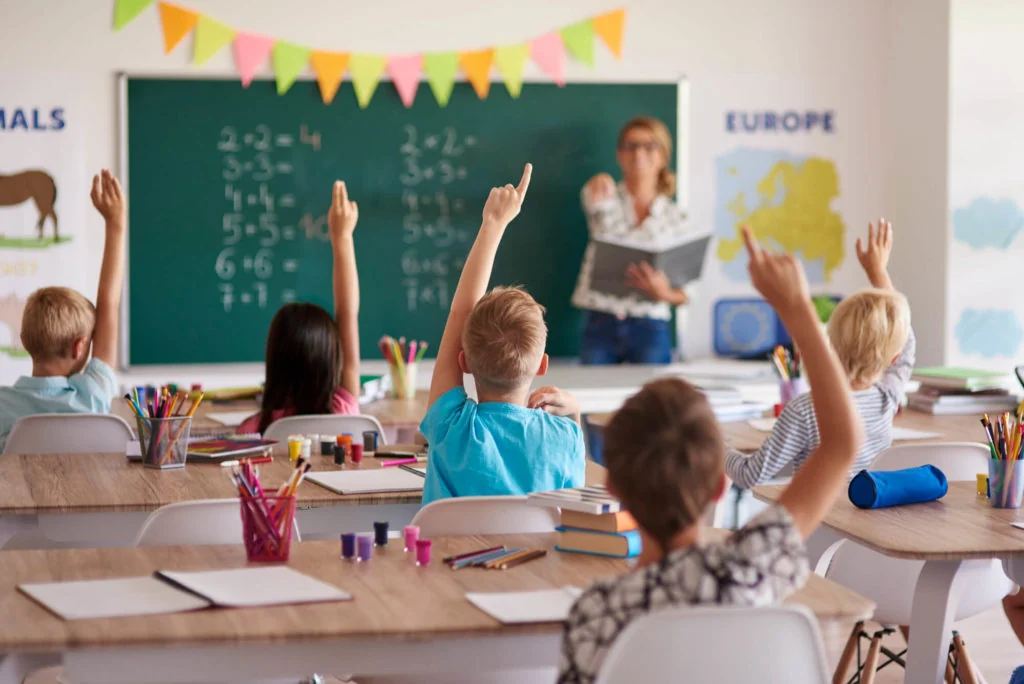 Students raising their hands in a classroom