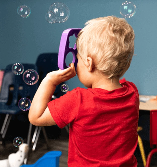 A child in a red shirt playing with bubbles