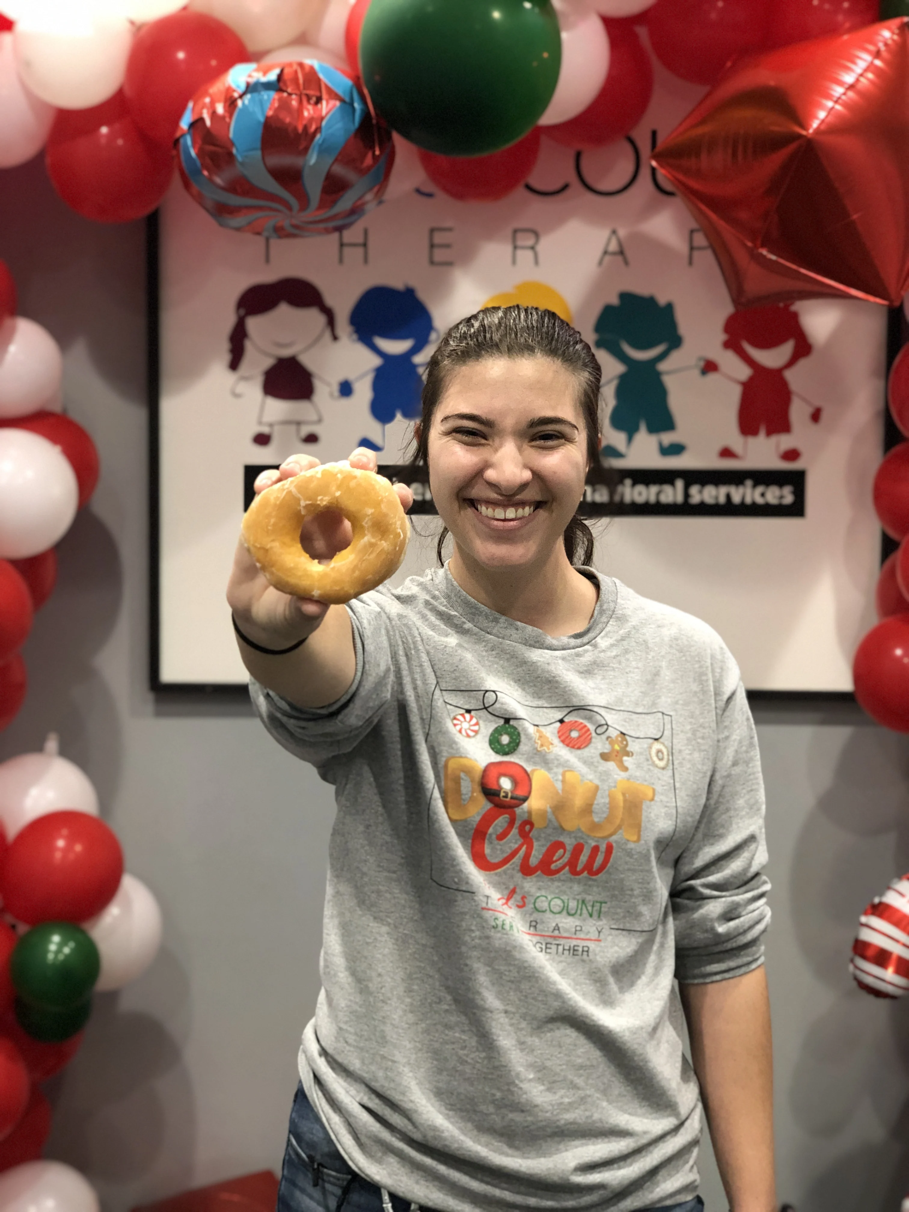 A team member holding up a donut at a holiday celebration
